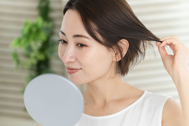 Woman checking scalp & hair in mirror